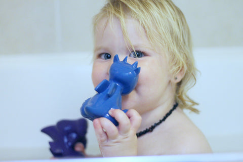 baby with teething toy in bath