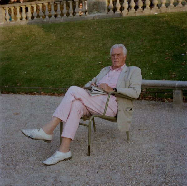 Man in grey jacket and pink pants sitting in a chair, photograph by film photographer Kir Lykkeberg