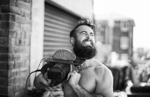 man trimming beard with electric saw