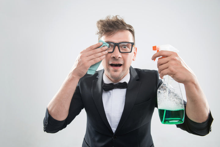 man wearing prescription glasses holding a microfiber cloth and dish soap
