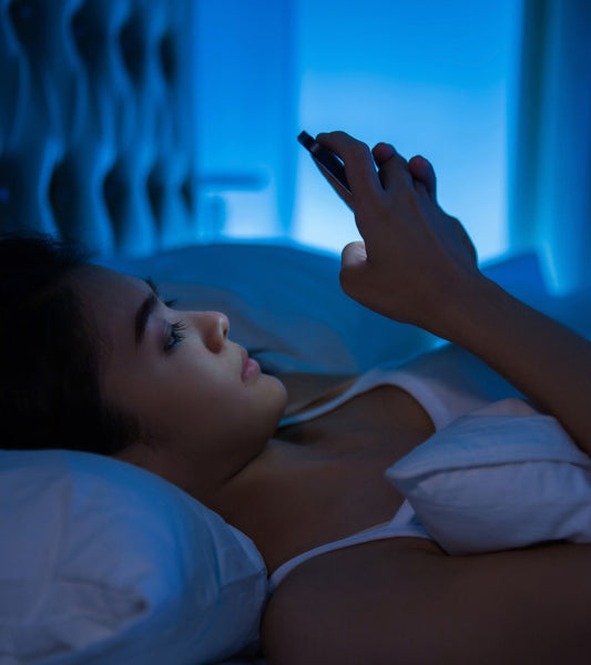 girl blue light on cell phone in bed
