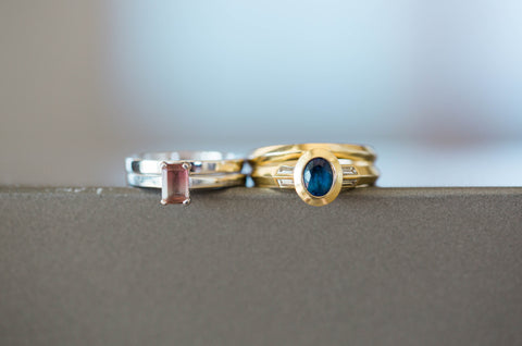 (Amy's ring left, emerald cut watermelon tourmaline, four claw set in platinum - Emily's ring, oval cut sapphire in rub-over setting, with baguette diamonds in yellow gold)