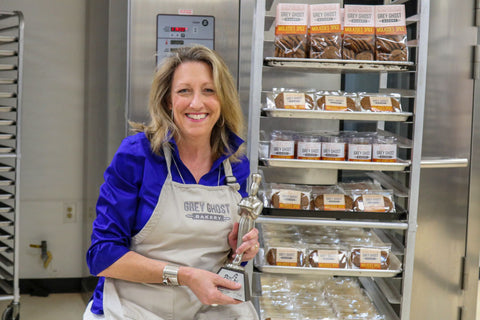 Katherine Frankstone Owner Grey Ghost Bakery Holding Silver Sofi award for Molasses Spice Cookies