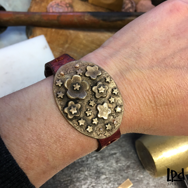 LPDstudios Blog: Behind the Scenes - Custom Bronze Flower Medallion Buckle Cuff - LPDstudios was created by designer artist Lisa Parmer Ditty. All of her designs are handcrafted in her Pennsylvania studio. She has merged her love of leather, metal and metal clay to create a unique collection of custom leather handbags, metal and leather jewelry and even pet collars. Follow her studio blog and see what she is designing next.
