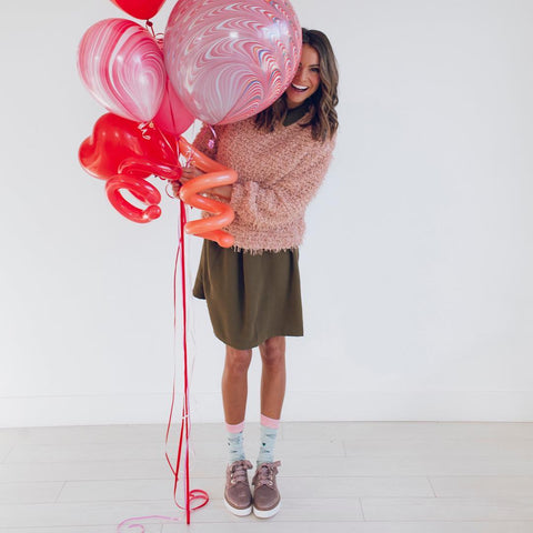 Girl holding balloons in Valentine's day outfit