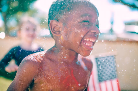 child in summer playing water american flag