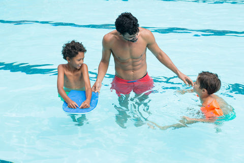 father talking to children in pool