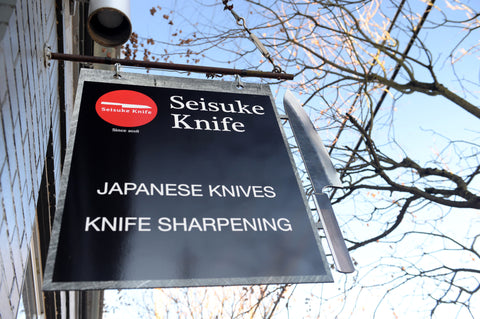 A photo of the store's sign that reads: Seisuke Knife Japanese Knives, Knife Sharpening