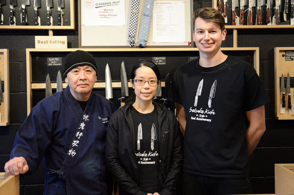 A photo of the Portland staff smiling for the camera in front of a portion of the wall display