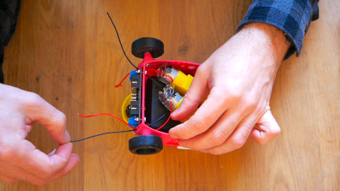 Image of two wires being pulled out of a pink 3D printed car