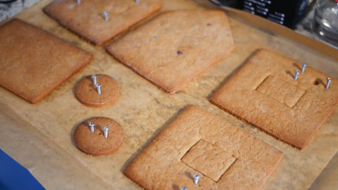 Image of sections of a gingerbread house with silver screws poked inside.