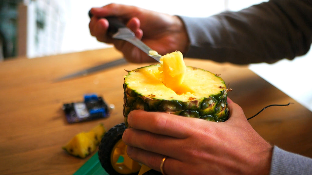 Chunks of pineapple are removed from a rectangular hole in the centre of the fruit