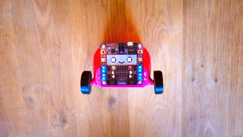 Image of a pink car with a purple circuit board on the front and black tires on each side.