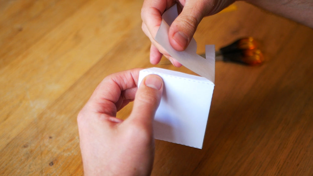 Photo of a paper tab folded from the top of the paper ghost being stuck to the side of the paper ghost