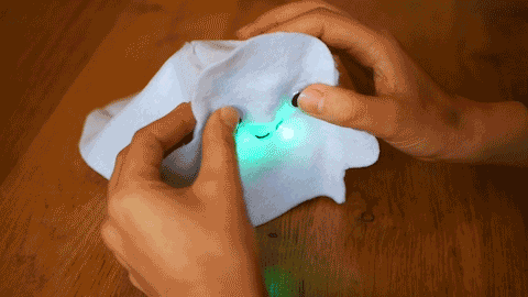 Looping video of two googly being pressed onto a white felt ghost with a glowing robot inside