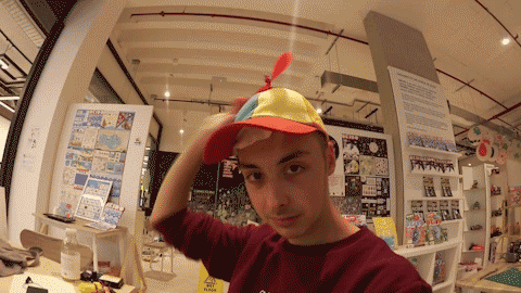 Looping video of young man wearing spinning the propeller on a multicoloured hat he is wearing