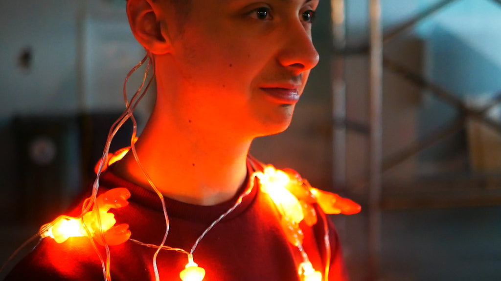 Photo of some lobster shaped fairy lights around the neck of a male teenager