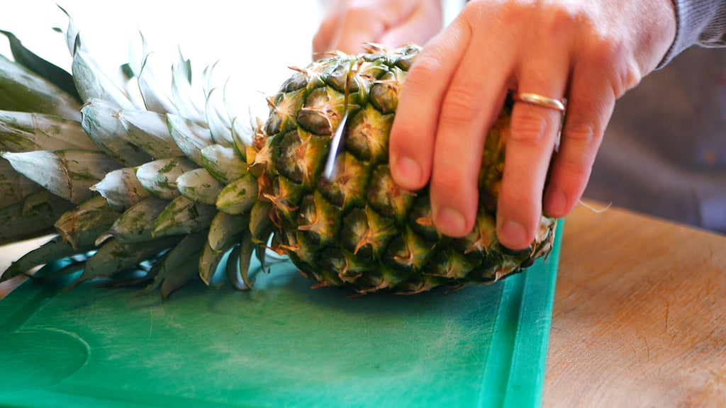 Pineapple being cut 1/3 of the way down from the top