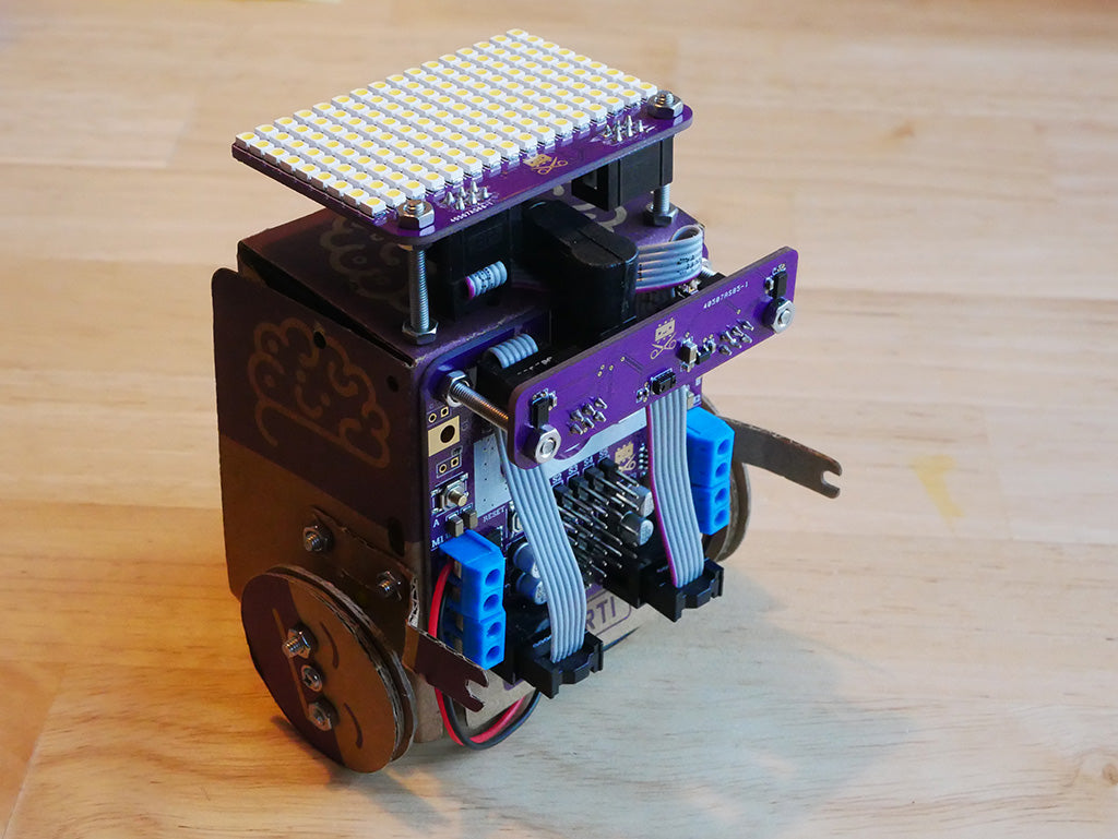 Photo of wheeled cardboard robot (Smartibot) with distance/gesture board mounted on the front and L.E.D. matrix on the rop