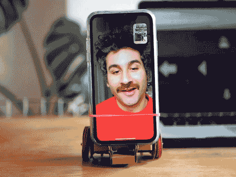 Looping video of a smartphone on a cardboard robot chassis displaying a man's face. Both the man and the robot are wiggling from side to side. 