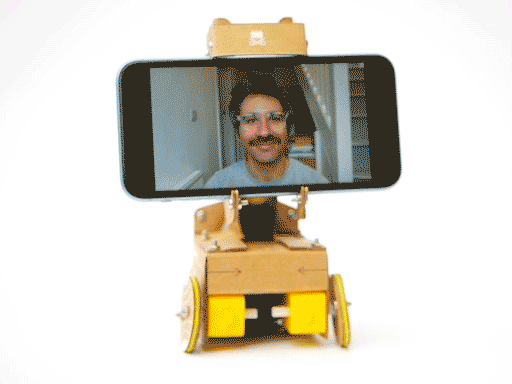 Looping video of a cardboard robot carrying a smartphone with a man's face on it moving from side to side