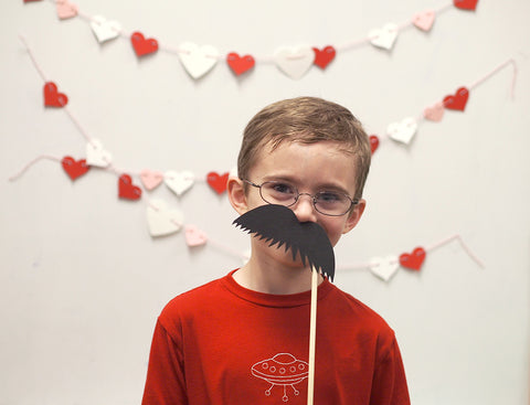 Mr6 sporting a handmade mustache photo prop at the photo booth at his school's Valentine's Day party