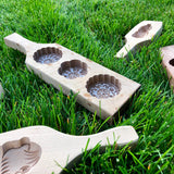 Wooden moon cake molds, a traditional Mid Autumn Festival food, shown laying scattered on dewy grass.