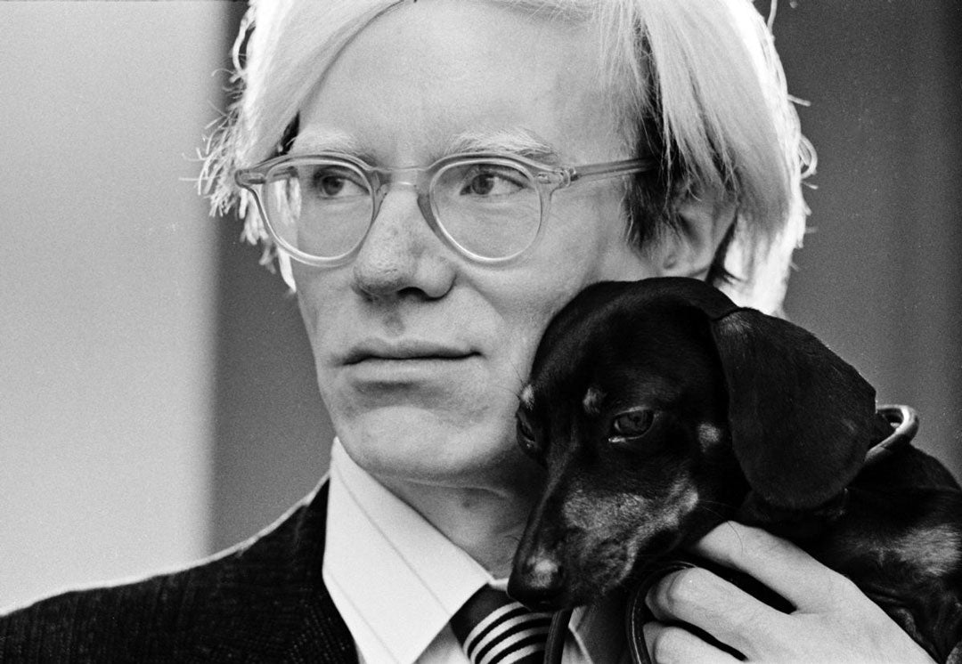 Andy Warhol holding his pet dog to his face