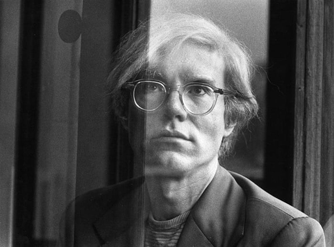 Andy Warhol looking through glass window wearing his clear frame spectacles
