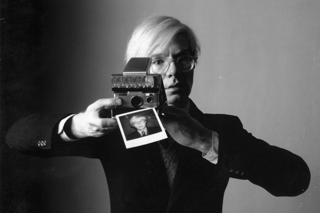 Andy Warhol taking a picture with a polaroid camera