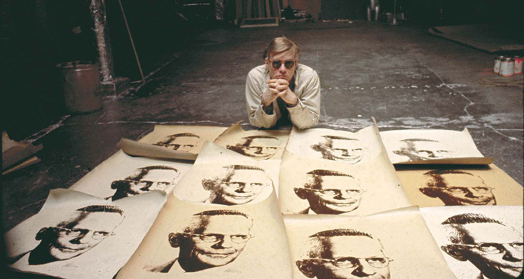 Artist Andy Warhol lying down in his studio wearing sunglasses