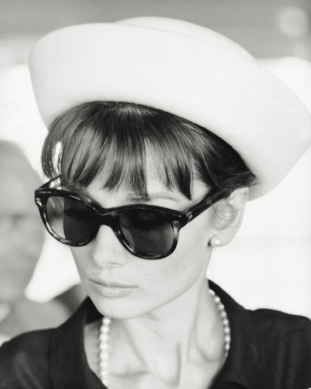 Audrey Hepburn wearing a white hat and large tortoise sunglasses
