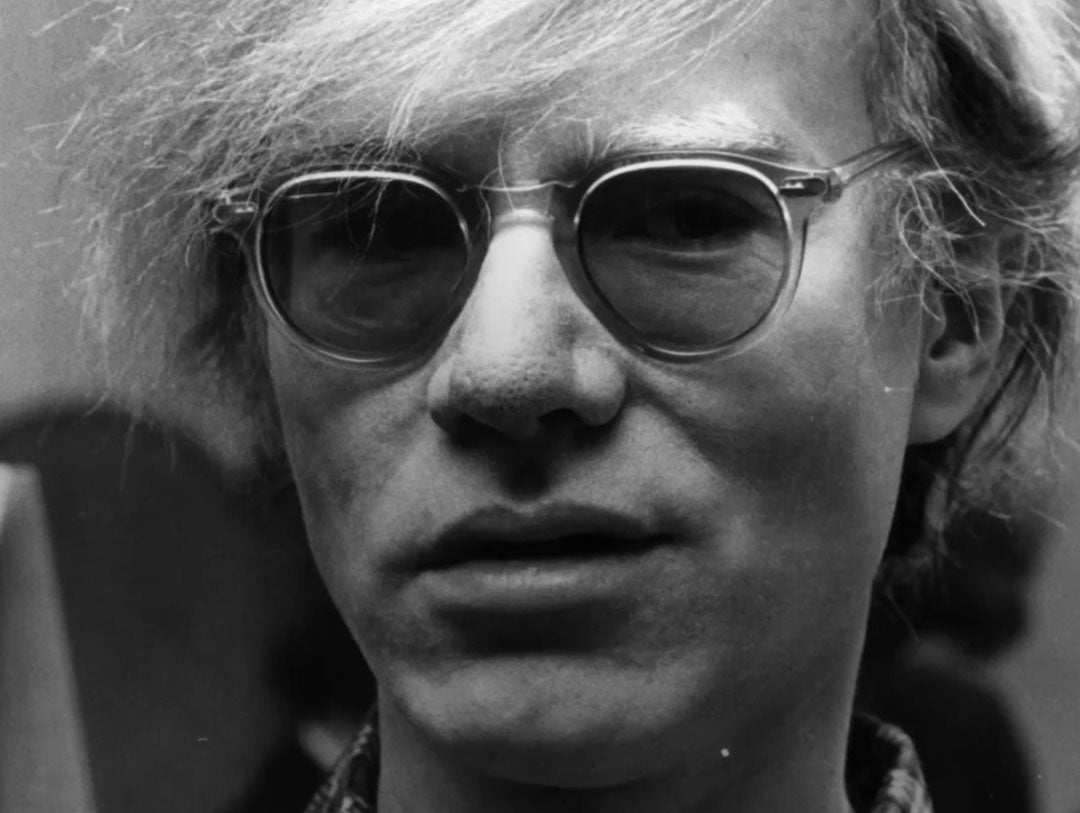 Close view of Andy Warhol wearing clear acetate sunglasses
