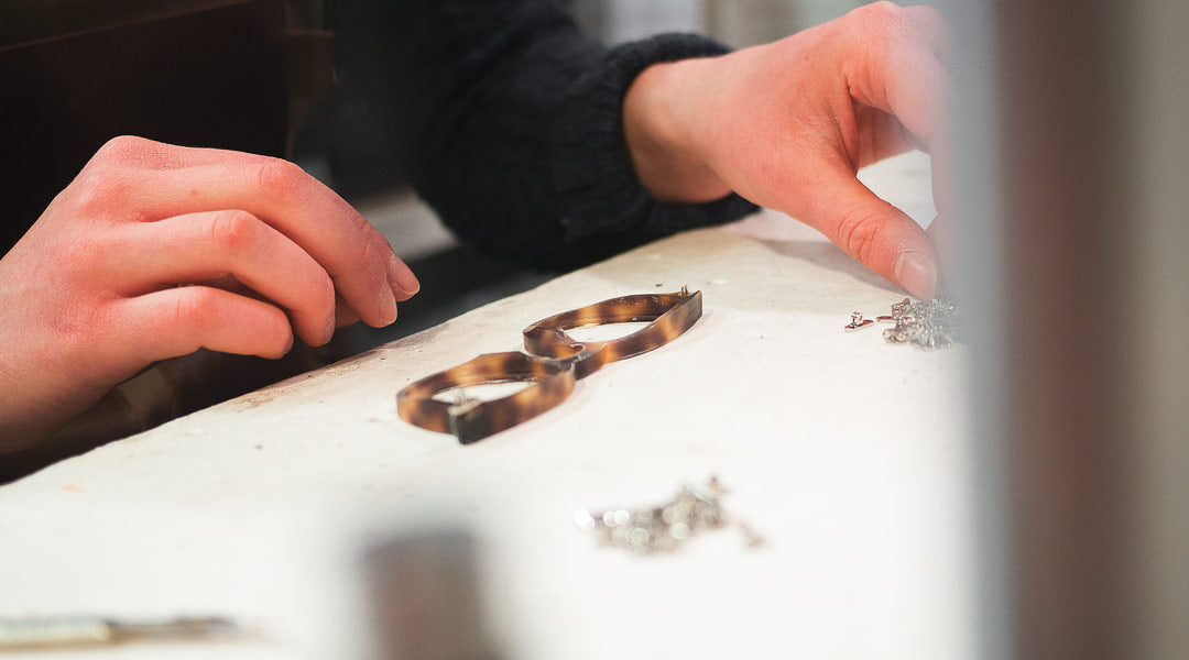 Female worker assembling a spectacle frame on a white workbench