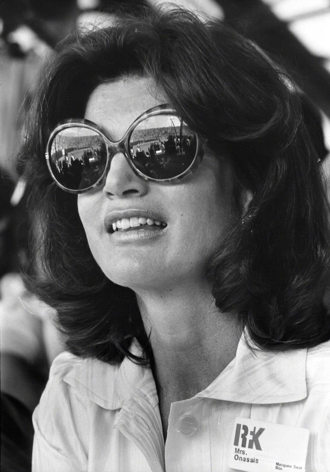 Jackie Onassis wearing large tortoise shell sunglasses at a sports event