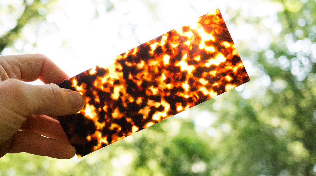 Man holding tortoise acetate sheet up to the sunlight