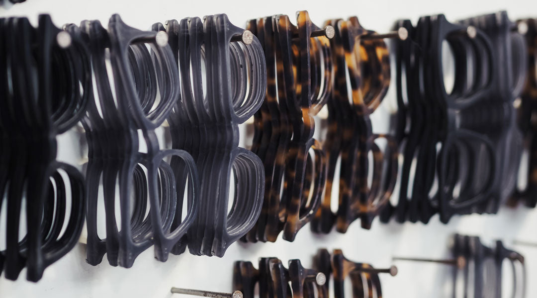 Rows of glasses frames hanging from pegs inside workshop