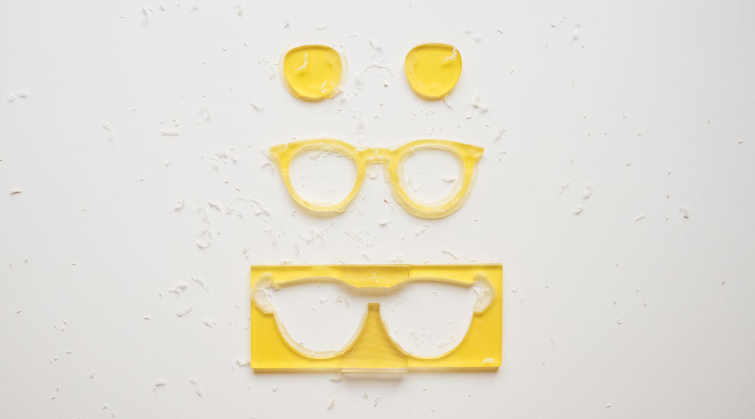 Yellow glasses design cut from acetate sheet on white table