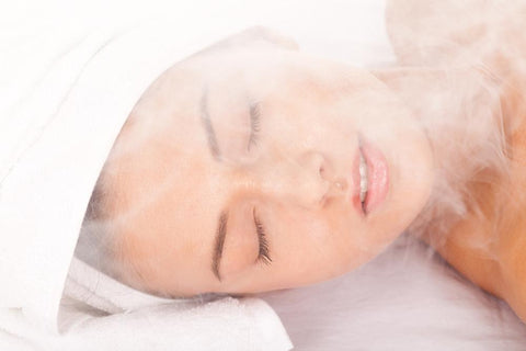 woman wearing a towel on her head and steaming her face to remove dead skin