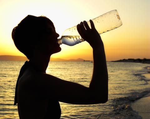 woman in a swimsuit drinking water on the beach