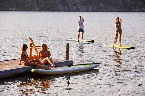 paddle boarders on a lake at sunset