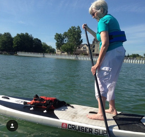 An eldery person riding a SUP