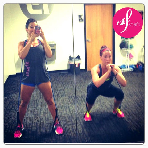 two women doing squats with rubber bands