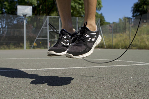 person jumping rope on outdoor basketball court
