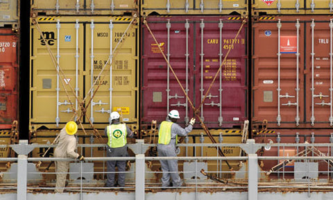 Workers lashing shipping containers with rods