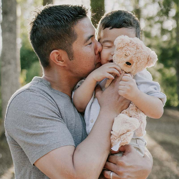 Caregiver holding child while child holds Honey Bear snuggler