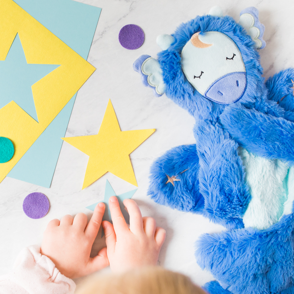 Child&#039;s hands touching a star cutout next to dragon plush