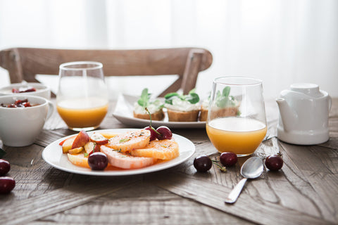 fruit on a plate on a wooden table with two glasses of juice