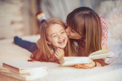 Mother laughing with daughter while reading a book
