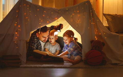 Father and kids reading together in a tent at home